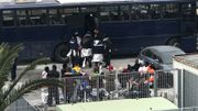 Les migrants récupérés durant la nuit sont triés et remonte dans un bus. Seuls cinq personnes assis le long d'une voiture sur la gauche ne remontent pas dans le bus. Les migrants récupérés durant la nuit sont triés et remonte dans un bus. Seuls cinq personnes assis le long d'une voiture sur la gauche ne remontent pas dans le bus.