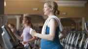 Pregnant Caucasian woman exercising on treadmill in gym Pregnant Caucasian woman exercising on treadmill in gym
