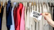 Second hand clothing shop. Used clothes hanging in hanger in a rack and wardrobe in a fashion store with discount and bargain prices. Woman holding advertising and marketing banner in hand. Second hand clothing shop. Used clothes hanging in hanger in a rack and wardrobe in a fashion store with discount and bargain prices. Woman holding advertising and marketing banner in hand.
