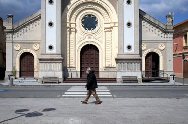 Passant avec un masque devant une église de Locri, en Calabre, le 08 avril 2020 Passant avec un masque devant une église de Locri, en Calabre, le 08 avril 2020
