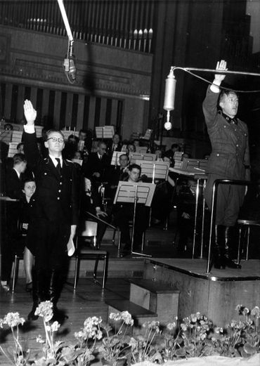 Place Flagey, concert à Radio Bruxelles – Zender Brussel, les radios contrôlées par les Nazis en Belgique pendant la Seconde Guerre mondiale. À droite, le chef de l’orchestre Paul Douliez en uniforme de la Waffen SS Place Flagey, concert à Radio Bruxelles – Zender Brussel, les radios contrôlées par les Nazis en Belgique pendant la Seconde Guerre mondiale. À droite, le chef de l’orchestre Paul Douliez en uniforme de la Waffen SS