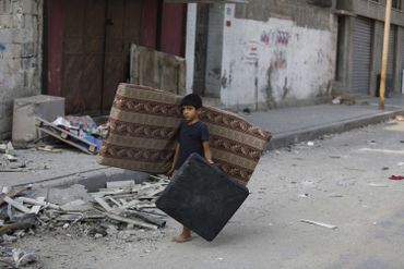 Un garçon palestinien transporte matelas et coussin de la maison démolie de ses parents dans le centre de Gaza city Un garçon palestinien transporte matelas et coussin de la maison démolie de ses parents dans le centre de Gaza city