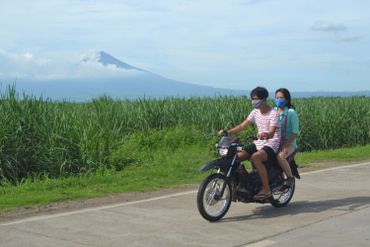 Des motards roulant sur une route avec le volcan Kanlaon en arrière-plan, vu depuis la ville d'Isabela, Negros Occidental, au centre des Philippines, le 24 juin 2020 Des motards roulant sur une route avec le volcan Kanlaon en arrière-plan, vu depuis la ville d'Isabela, Negros Occidental, au centre des Philippines, le 24 juin 2020