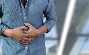 Midsection Of Man Touching Abdomen While Standing Against White Background Midsection Of Man Touching Abdomen While Standing Against White Background